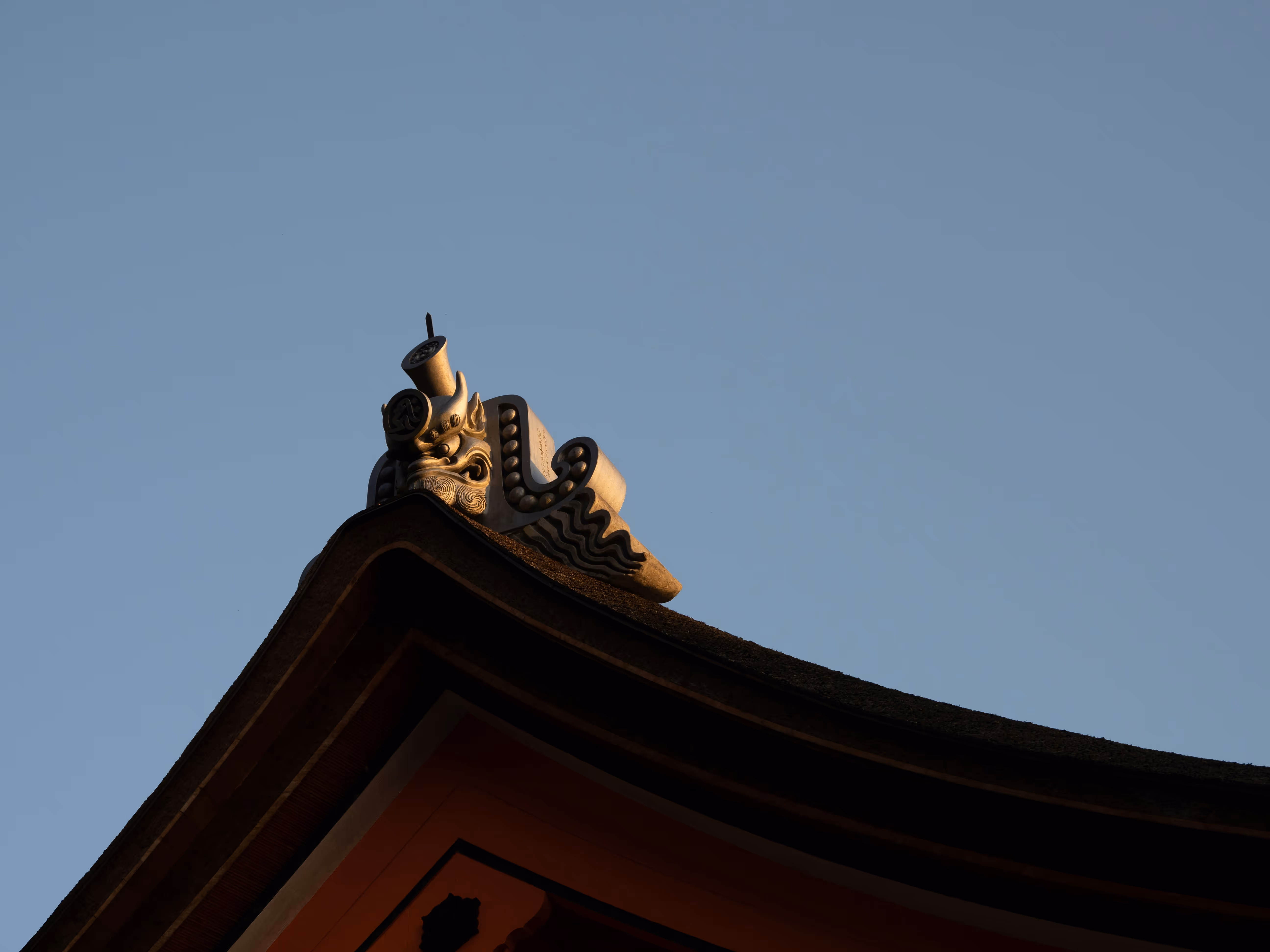 A temple roof ornament in Kyoto, caught in evening light against a clear sky